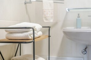 Casa de banho com lavatório, um porta-toalhas com toalhas dobradas e uma sanita.