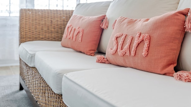 A wicker sofa with white cushions and pink pillows with tassels. - Casa da Adega - Holiday Home 2 Minutes from the Beach (Ribeira Chã)