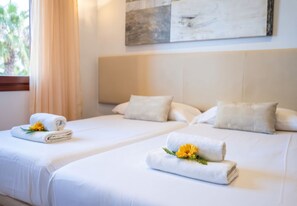 A hotel room with two beds, each with a neatly folded white towel and a yellow flower. - Finca Eden Son Manyo 222 with pool in Mallorca (Sa Pobla)