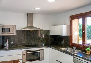 A modern kitchen with a built-in microwave, oven, and stainless steel range hood. - Finca Eden Son Manyo 222 with pool in Mallorca (Sa Pobla)