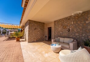 A covered outdoor area with stone walls, a sofa, and a coffee table.