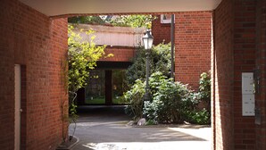 A brick building with a covered entrance, a street lamp, and a small garden area with plants and a pathway. - Exclusive maisonette 83sqm, quiet, central location, in the old town (Lüneburg)