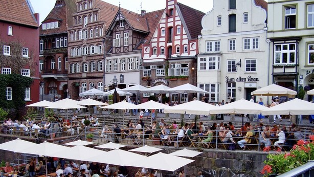 A riverside restaurant with outdoor seating, surrounded by historic buildings. - Exclusive maisonette 83sqm, quiet, central location, in the old town (Lüneburg)