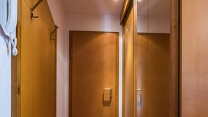 A hallway with wooden doors, a coat rack, and a telephone.