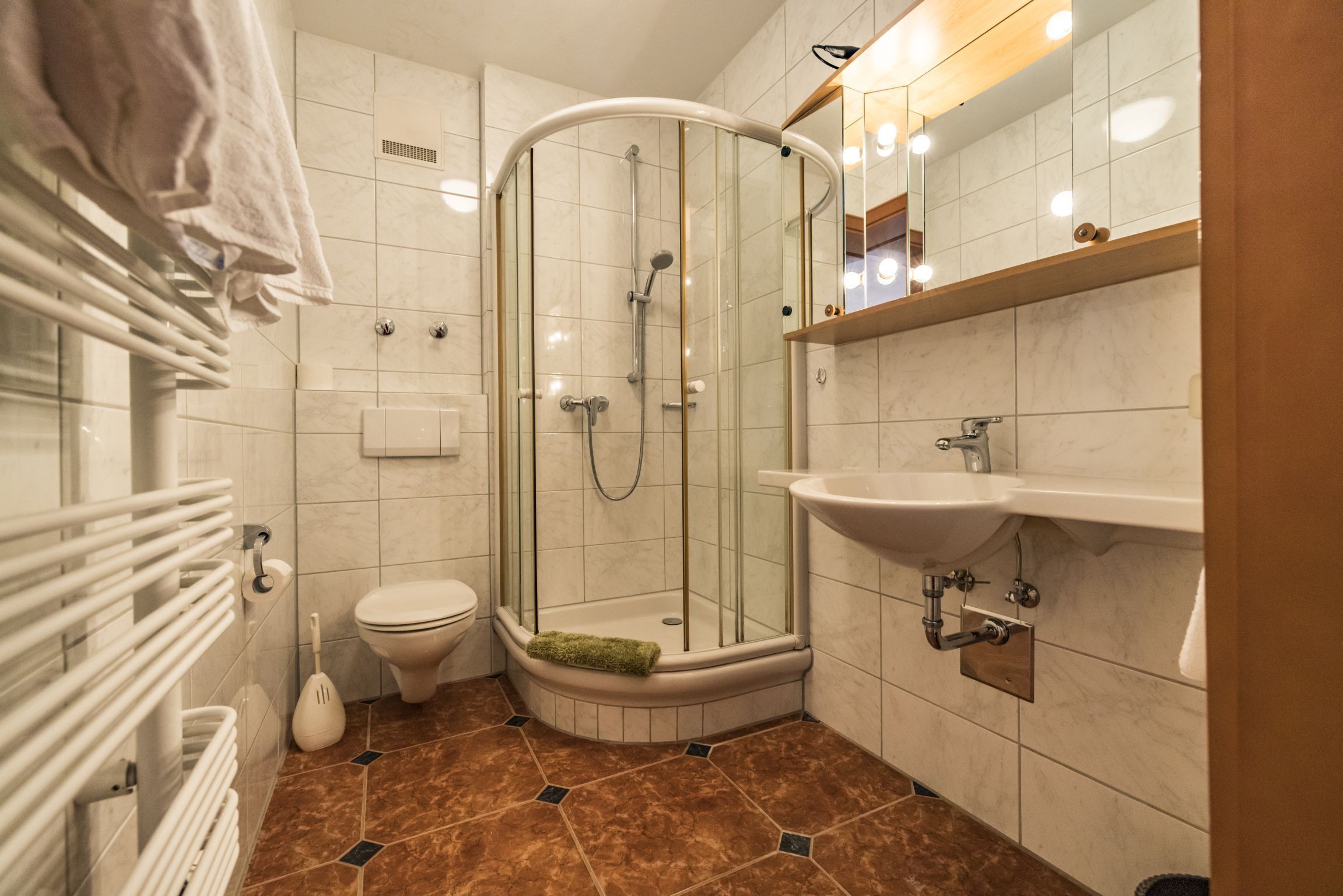 A modern bathroom with a glass-enclosed shower, a toilet, and a sink.