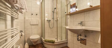 A modern bathroom with a glass-enclosed shower, a toilet, and a sink.