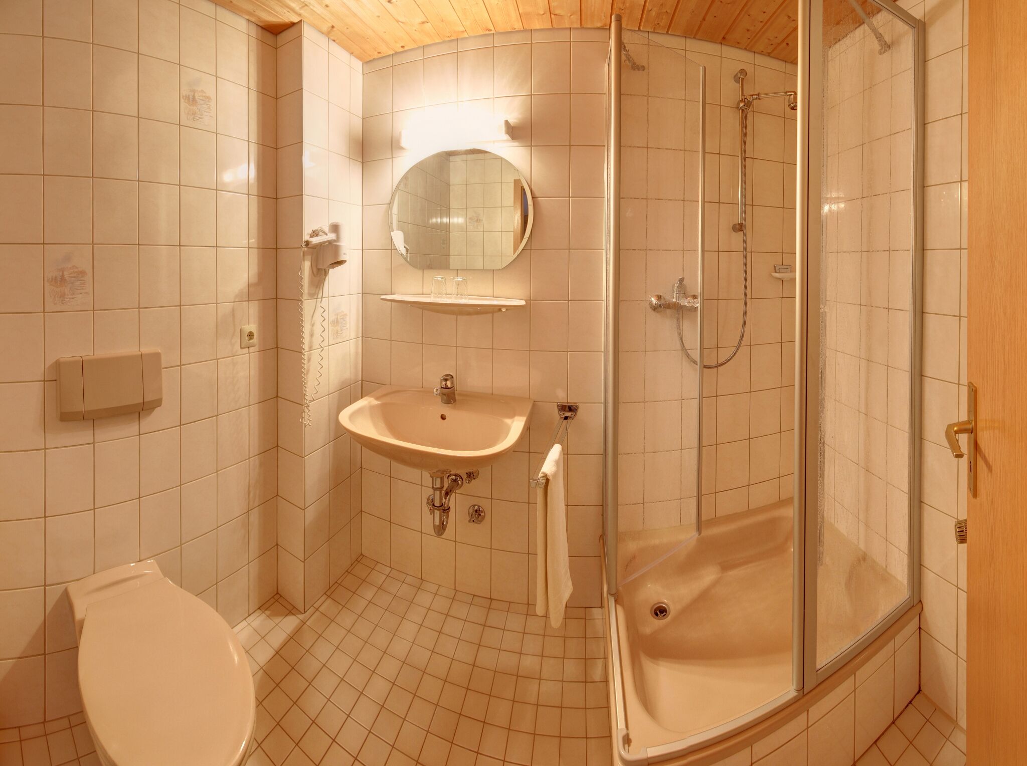 A bathroom with a toilet, sink, mirror, and shower.