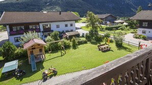 Un pueblo rural con casas tradicionales, un parque infantil y montañas al fondo.