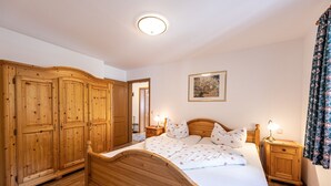 Ein Schlafzimmer mit einem Holzbett, einem Kleiderschrank und einem Nachttisch mit Lampen.