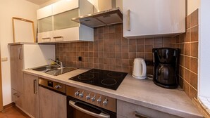 Eine kleine Küche mit Gasherd, Backofen, Geschirrspüler und einer Kaffeemaschine.