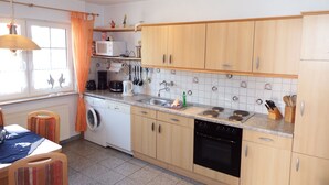 Una cocina con armarios de madera, microondas, cafetera y lavavajillas.