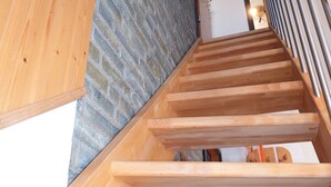 Una escalera de madera con un muro de piedra a un lado y una barandilla de madera al otro.