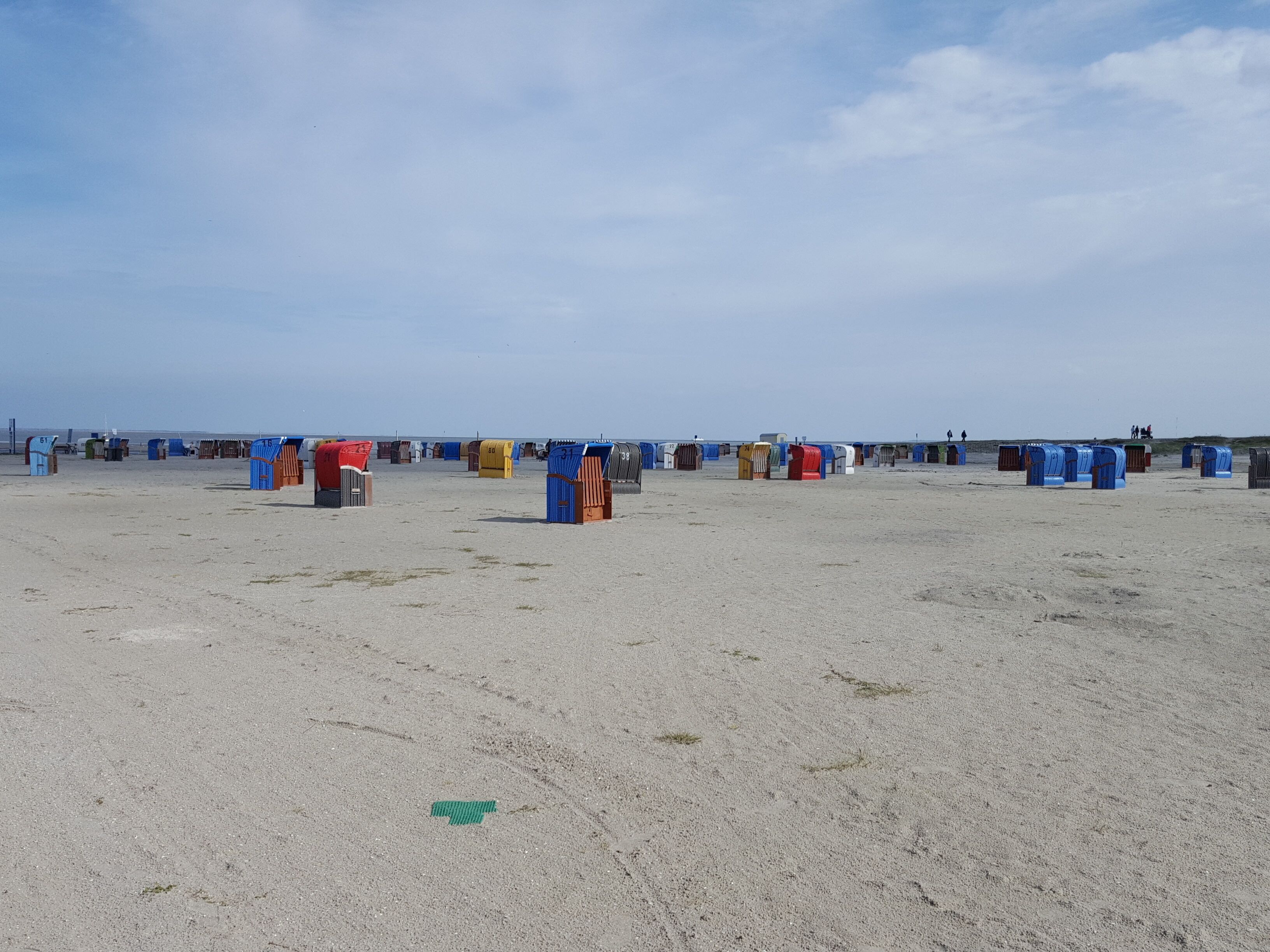 A beach with numerous colorful beach huts arranged in rows.