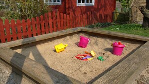 En sandlåda med sand, en träram och ett rött staket.
