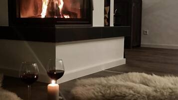 Ein gemütliches Zimmer mit Kamin, zwei Gläsern Rotwein und einem flauschigen Teppich.