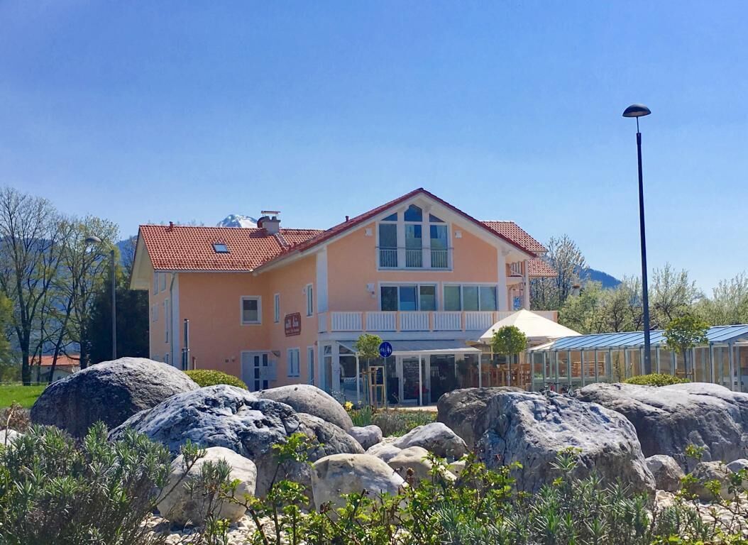 Ein zweistöckiges Gebäude mit rotem Ziegeldach, großen Fenstern und einem Balkon.