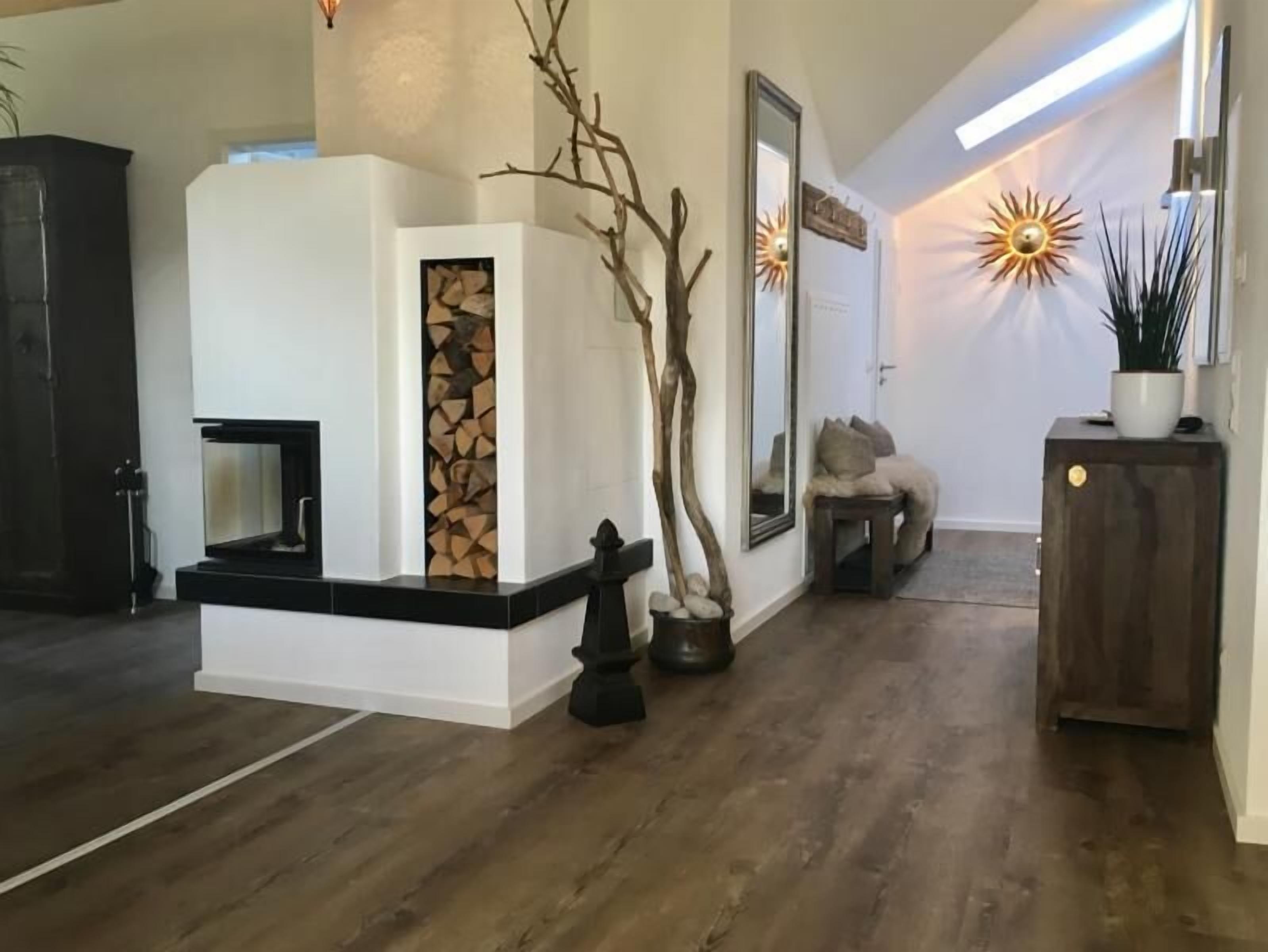 Ein modernes Wohnzimmer mit Kamin, einem großen Spiegel und einer Wanddekoration im Sonnenstrahl-Design.