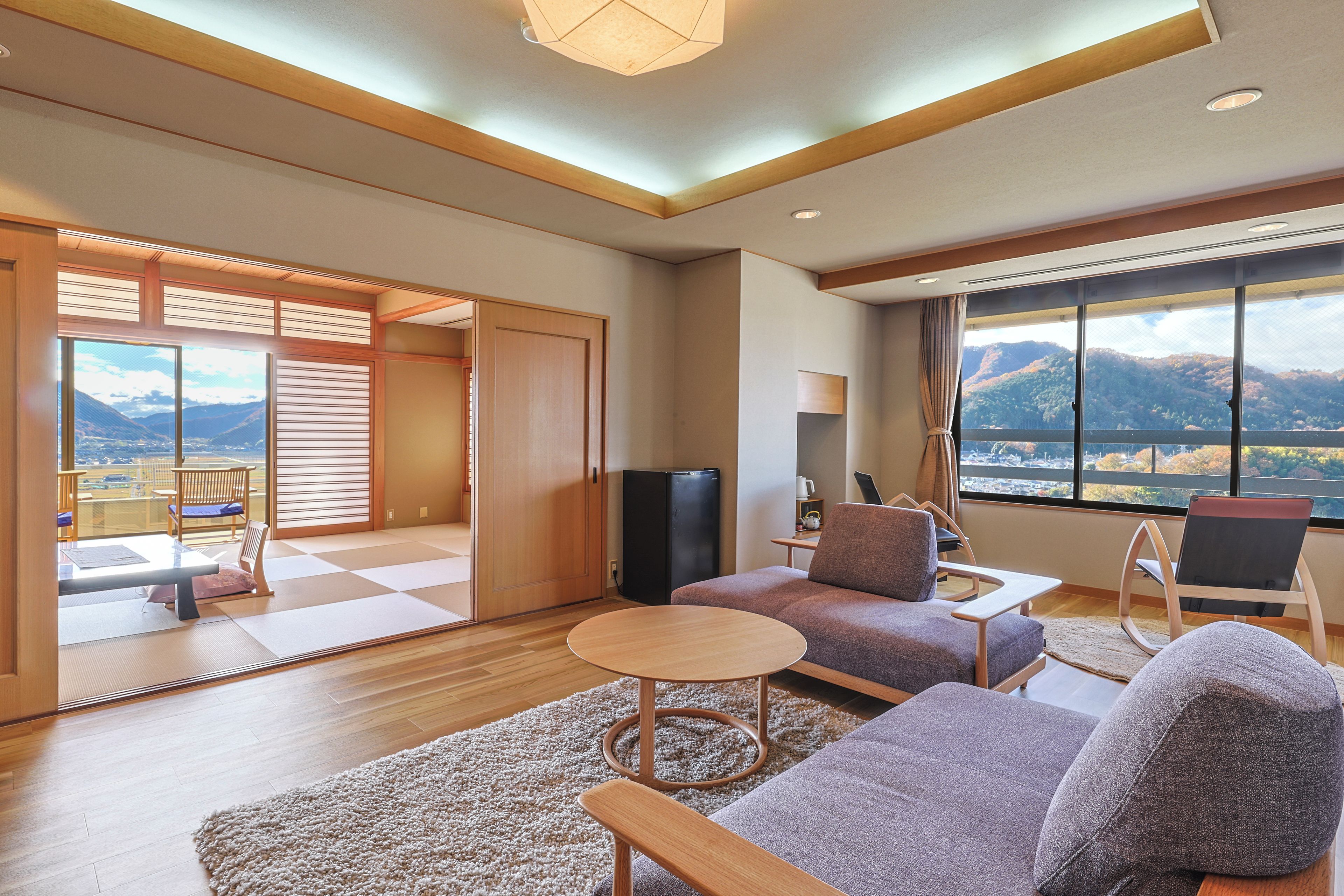 A modern living room with a sofa, a coffee table, and a view of mountains through large windows.