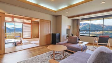 A modern living room with a sofa, a coffee table, and a view of mountains through large windows.