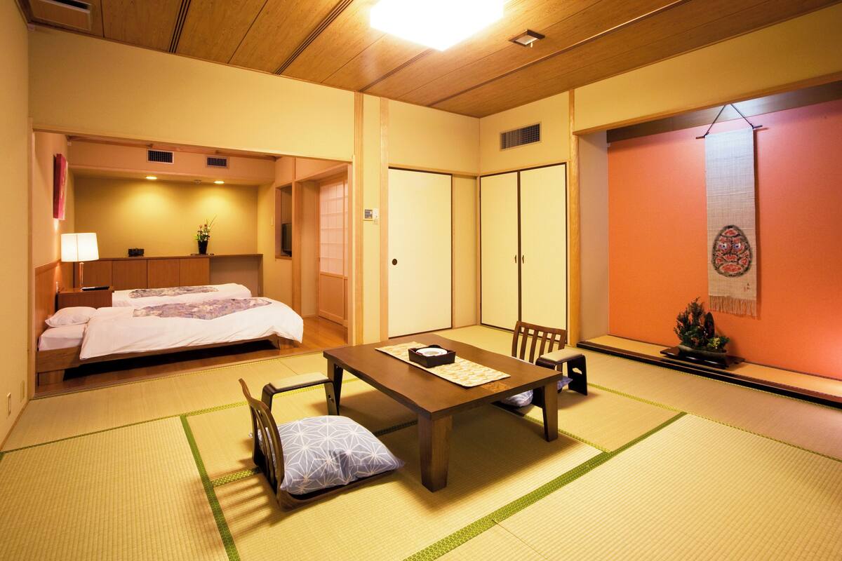 A traditional Japanese room with tatami flooring, a low wooden table, and a futon bed.