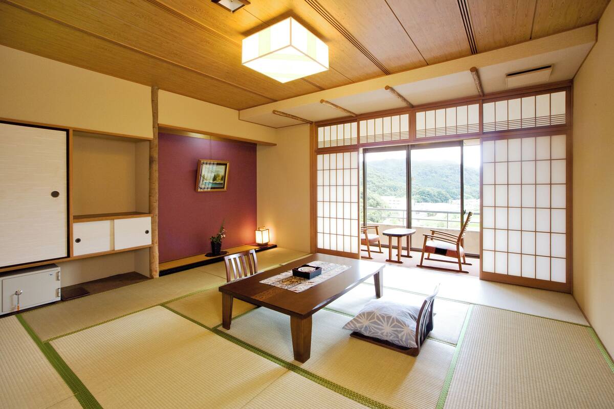 A traditional Japanese room with tatami flooring, a low wooden table, a cushioned bench, and sliding shoji doors.