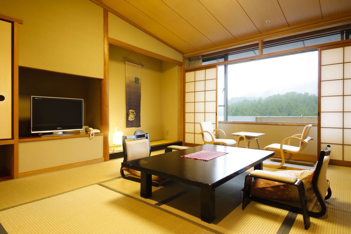 A traditional Japanese room with tatami flooring, a low table, and several chairs.