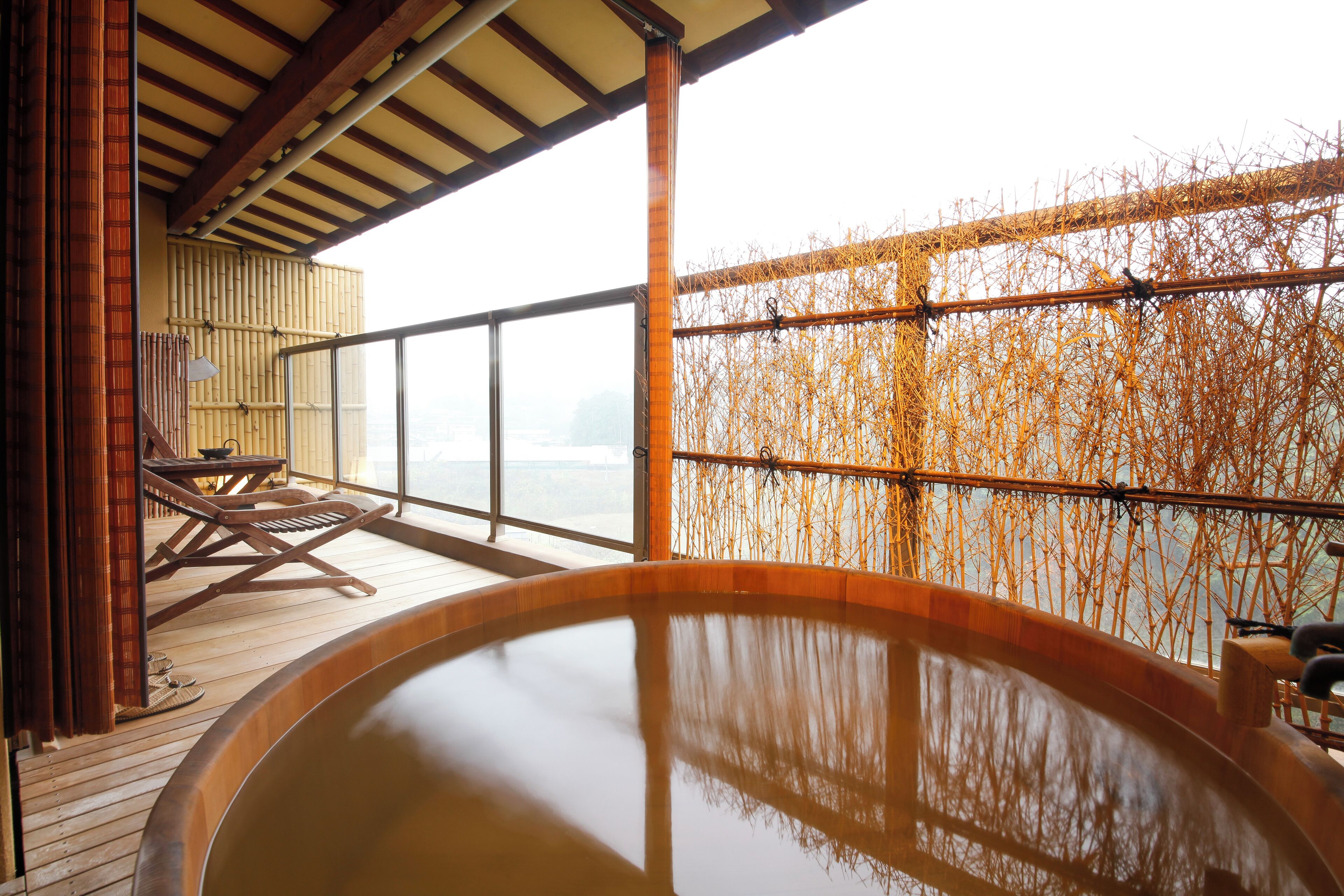 Ein Whirlpoolbereich mit Holzterrasse, Bambuswand und Blick auf das Wasser.