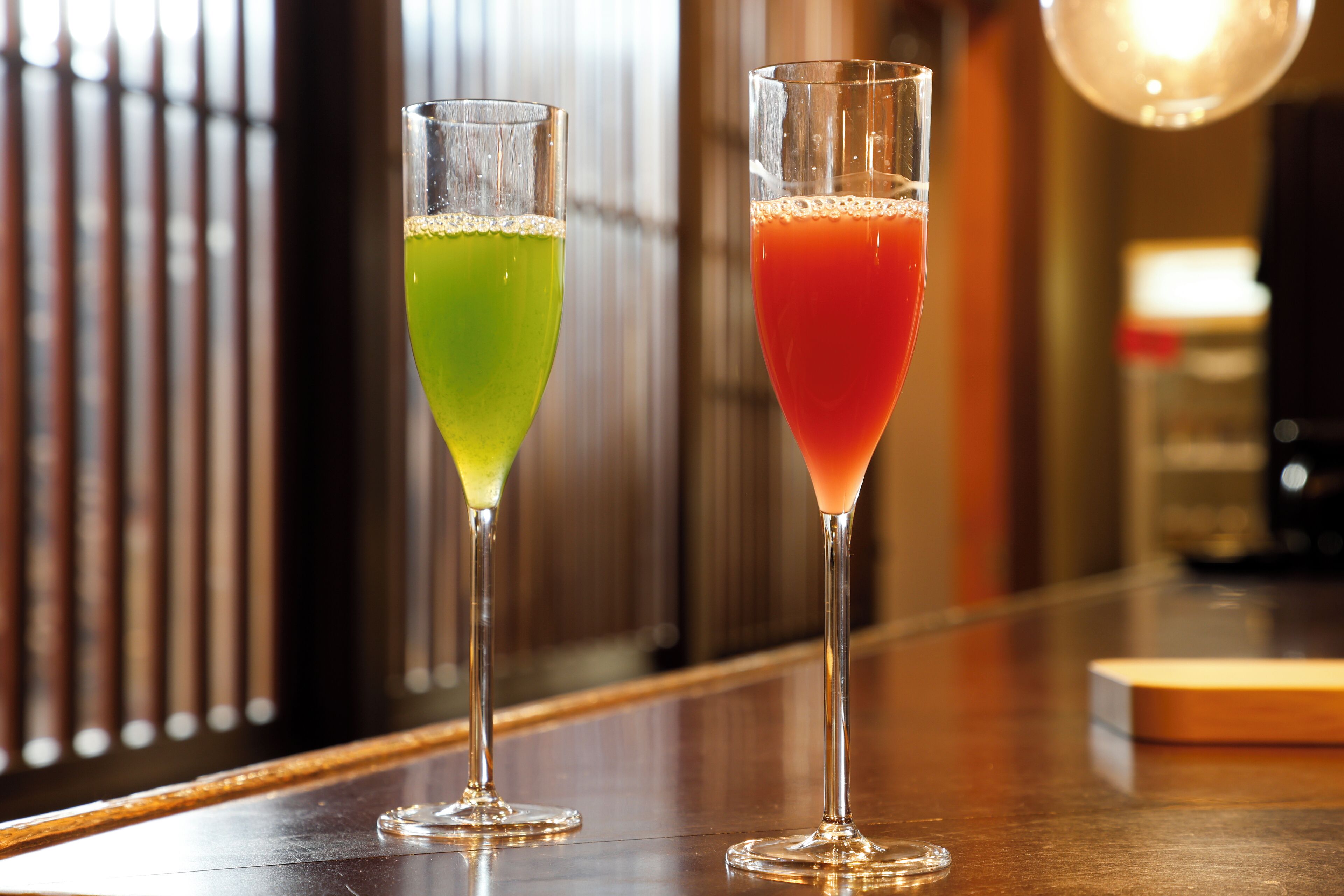 Two glasses of cocktails on a bar counter.