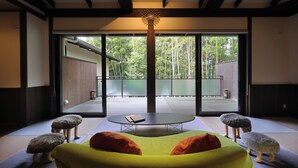 Un intérieur moderne avec un canapé vert, une table ronde et une vue sur un balcon doté d’une balustrade.