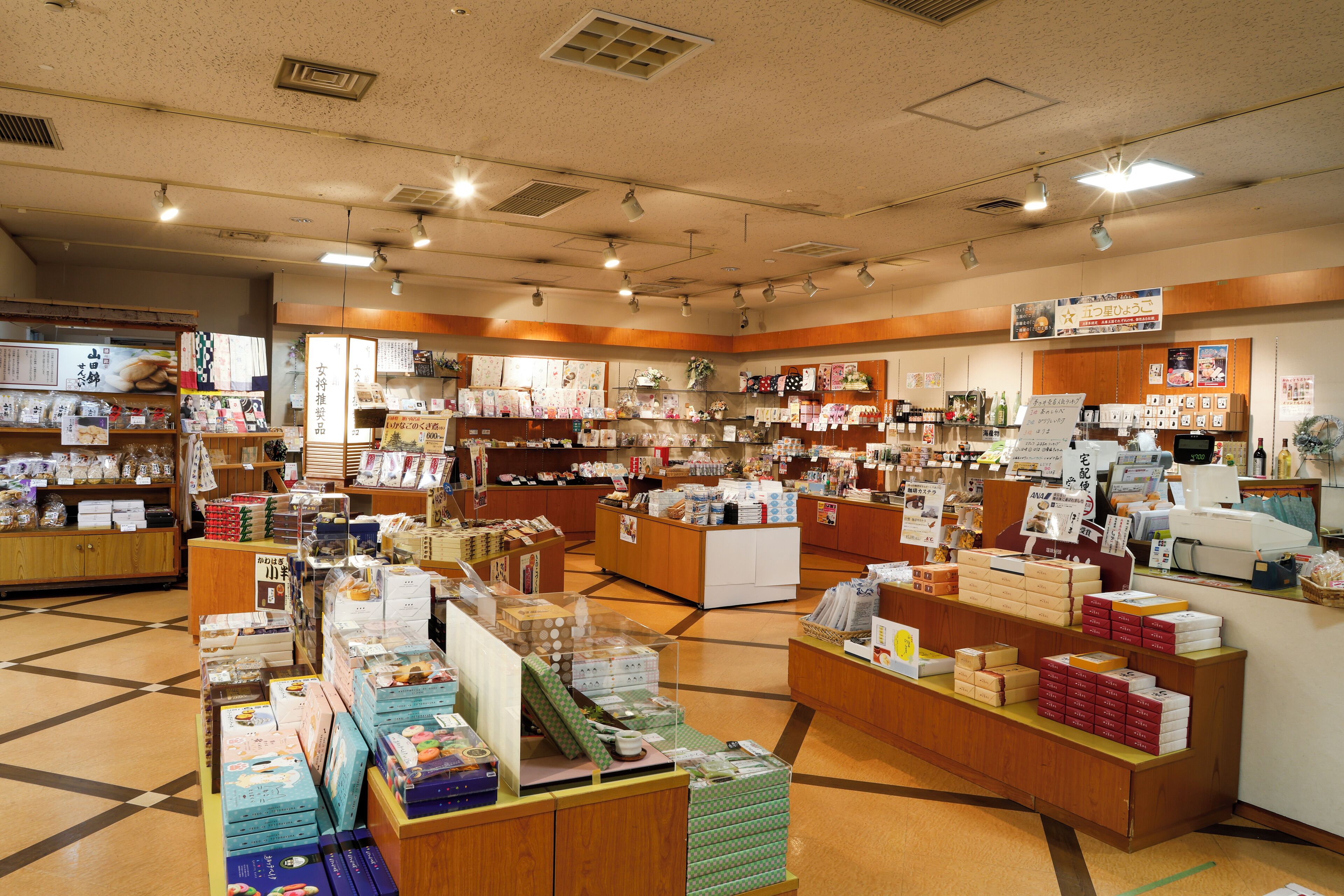 Una tienda bien iluminada con diversos productos en estantes y mostradores, incluyendo cajas y artículos envasados.