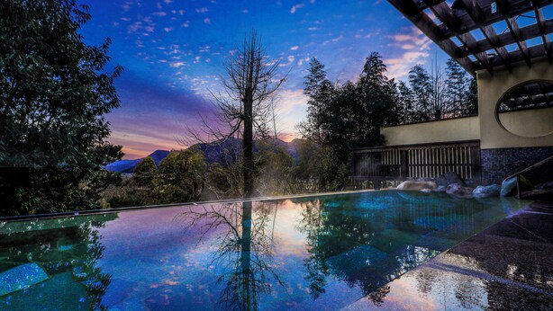 Une étendue d’eau limpide où se reflètent les arbres et le ciel au coucher du soleil.