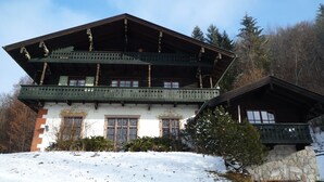 A traditional chalet with a steep roof, wooden balconies, and a stone foundation. - Ferienhaus für 2 Personen (Berchtesgaden)