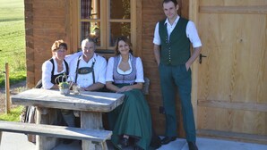 Une cabane en bois avec une porte et une fenêtre en bois, une table de pique-nique et une personne debout à côté.