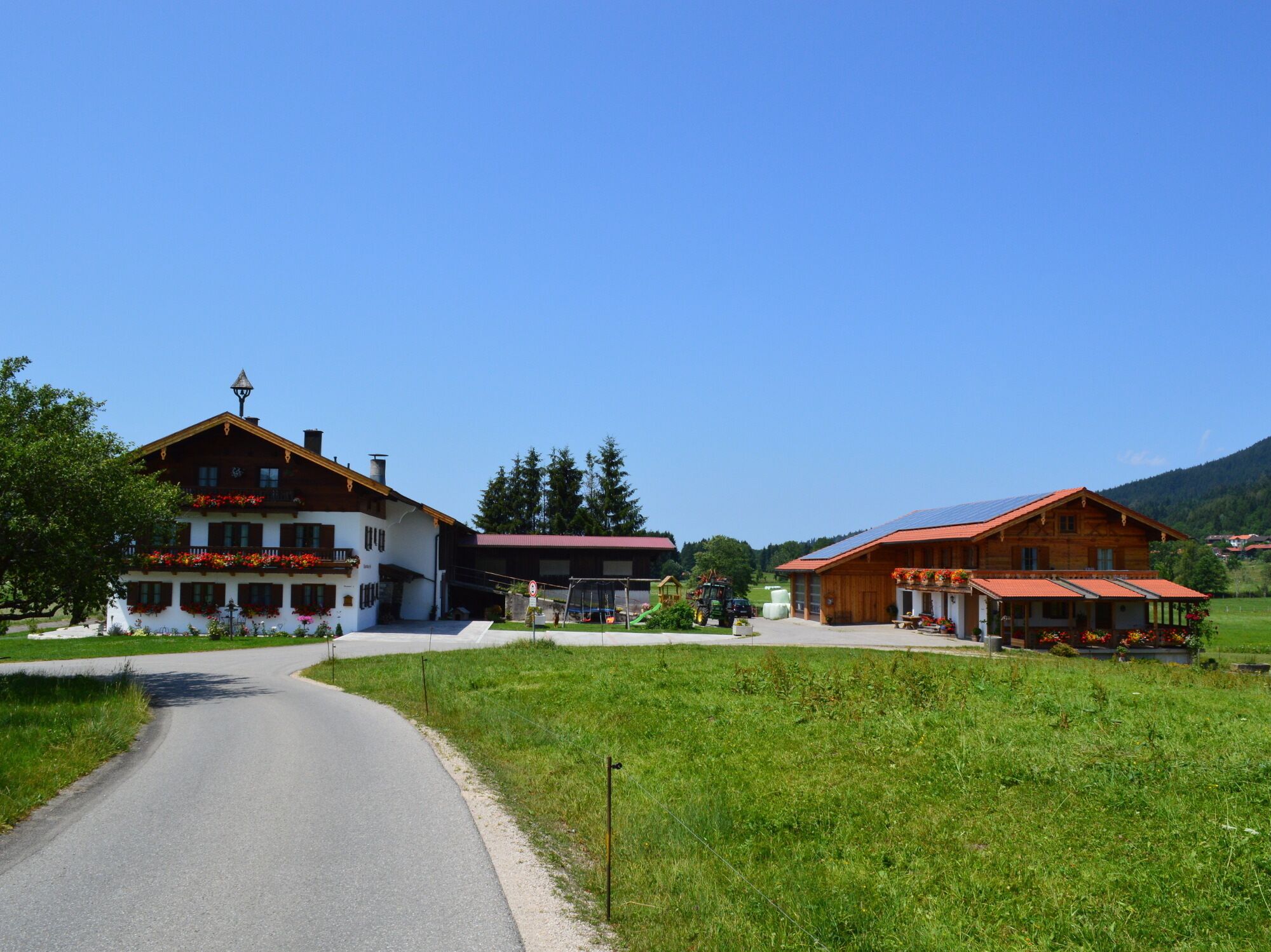 Ländliche Szenerie mit einer Straße, die zu einem Gebäude mit Balkon und Blumenkästen führt.