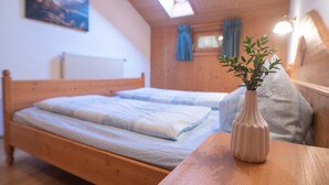 Un lit en bois avec un matelas blanc et un vase contenant des feuilles vertes, posé sur une table en bois.