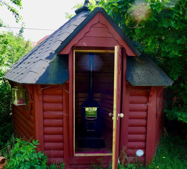 Una cabaña pequeña de madera roja con techo inclinado y una puerta de acceso.