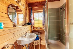 Ein Badezimmer einer Holzhütte mit Waschbecken, Spiegel und Dusche.