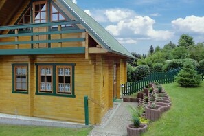 Eine Holzhütte mit einem grünen Dach, einer Veranda und einem Garten mit erhöhten Blumenkästen.