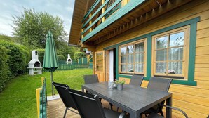 Une cabane en bois dotée d’une terrasse, d’un espace salon extérieur et d’un barbecue.