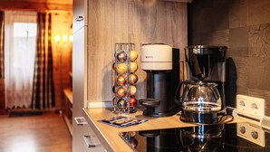 Une cuisine équipée d’une machine à café, d’une bouilloire et d’un étagère à épices.