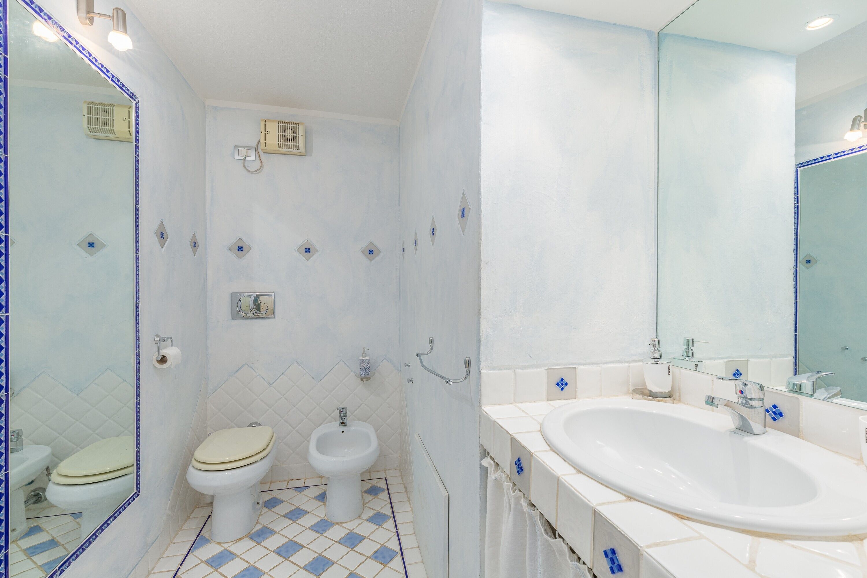 A bathroom with a toilet, bidet, and a large sink.