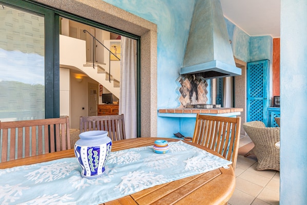 A dining area with a table set for two, a blue and white patterned vase, and a blue and white patterned tablecloth.