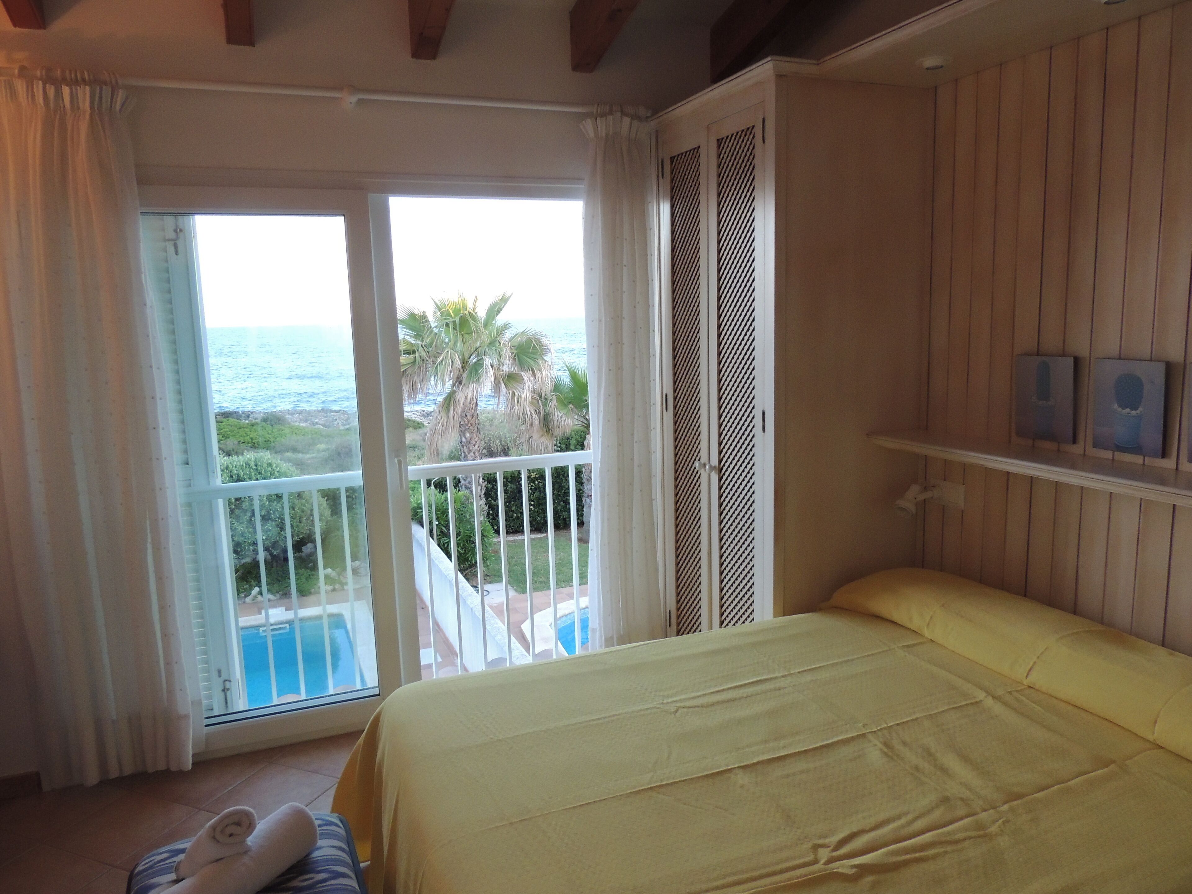 Ein Schlafzimmer mit Bett, Meerblick und einem Balkon mit Pool.