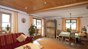 Un salon chaleureux avec un canapé, une table à manger et des chaises, ainsi qu’un buffet en bois.