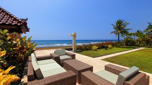 Um espaço de relaxamento à beira-mar com mobiliário de vime e vista para o oceano.