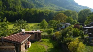 A rural village with traditional houses, a stone building, and a mountain in the background. - Ferienwohnung mit Bergblick (Flintsbach am Inn)