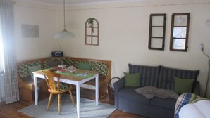 Ein gemütliches Wohnzimmer mit Essbereich, inklusive einer Couch, einem Tisch und einer Bank.