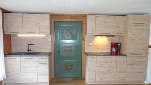 A compact kitchen with wooden cabinets, a sink, and a coffee maker. - B Apartment Branderalm 52sqm, balcony, eat-in kitchen, 2 bedrooms, 1 bed-sitting room (Ruhpolding)