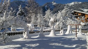 Paisaje nevado con una cabaña de madera y árboles cubiertos de nieve.