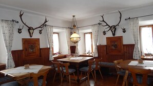 Une salle à manger avec des meubles en bois, un lustre et des décorations en forme de bois de cerf aux murs.